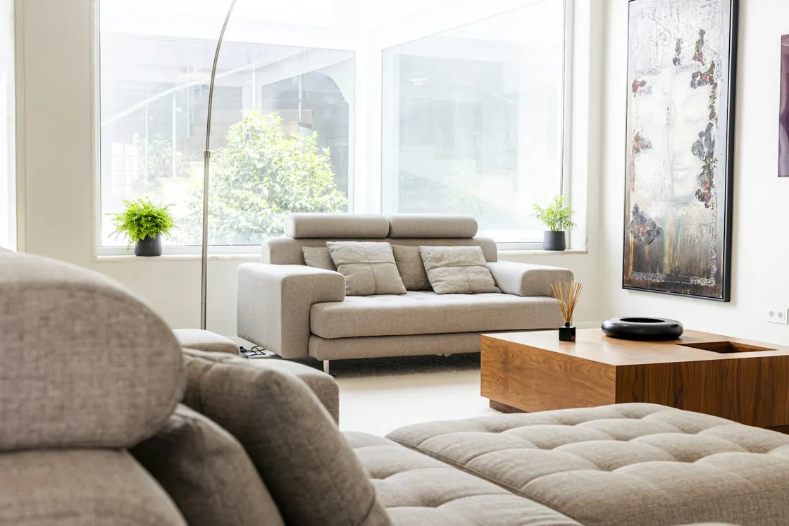 Bright living room with light sofas, wood and large windows.